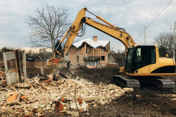 excavator-destroying-brick-house-on-land-in-countr-2023-11-27-05-20-09-utc